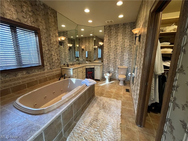 bathroom featuring toilet, a bidet, vanity, and tiled bath