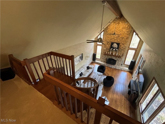 living room featuring a fireplace, high vaulted ceiling, hardwood / wood-style floors, beamed ceiling, and ceiling fan