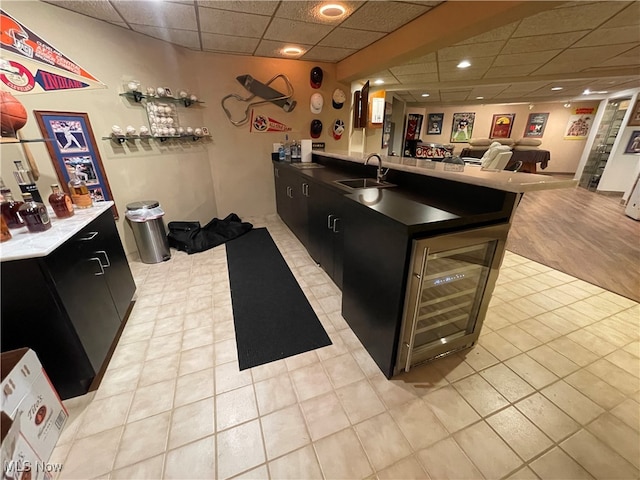 kitchen with a drop ceiling, sink, light tile patterned floors, and a kitchen island with sink