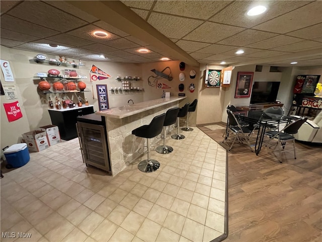 bar featuring a paneled ceiling and wine cooler