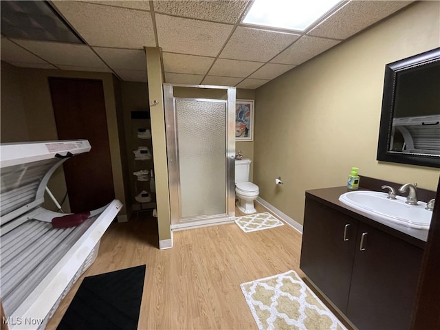 bathroom with walk in shower, vanity, hardwood / wood-style floors, toilet, and a drop ceiling