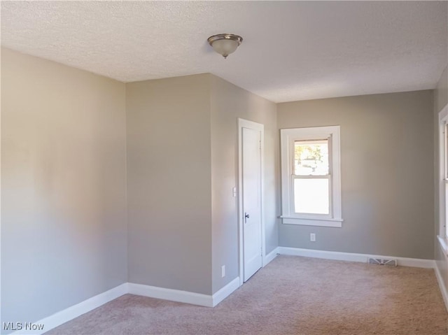 spare room with light carpet and a textured ceiling