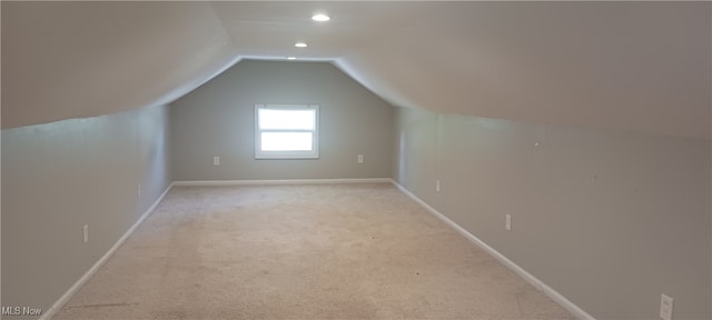 additional living space featuring light carpet and vaulted ceiling