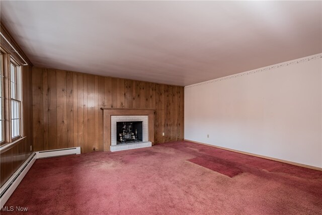 unfurnished living room featuring wood walls, a baseboard radiator, a brick fireplace, and carpet floors