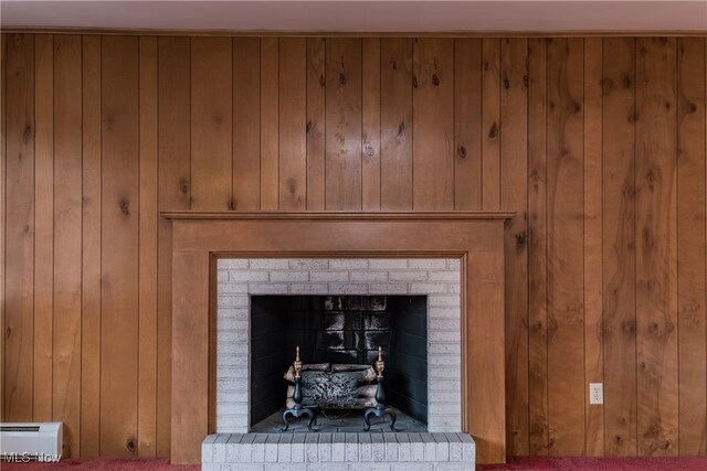 room details featuring a baseboard heating unit, a fireplace, wood walls, and carpet floors