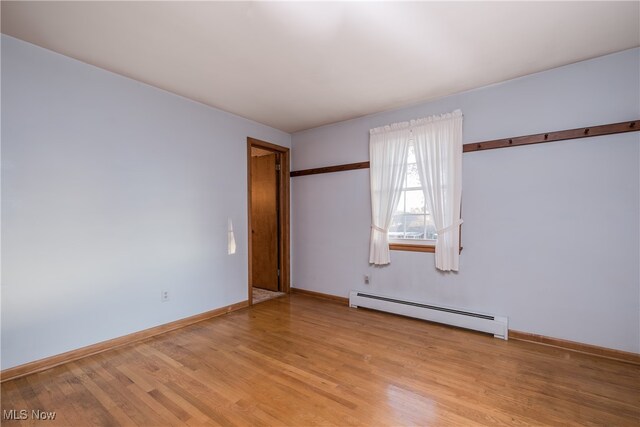 empty room featuring light hardwood / wood-style floors and a baseboard heating unit