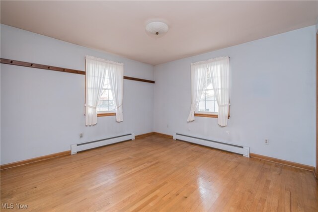 spare room with a wealth of natural light, a baseboard radiator, and light hardwood / wood-style flooring