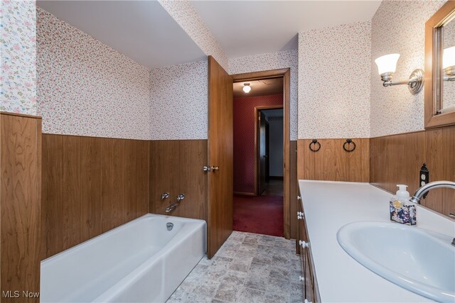 bathroom with wood walls, vanity, and a tub