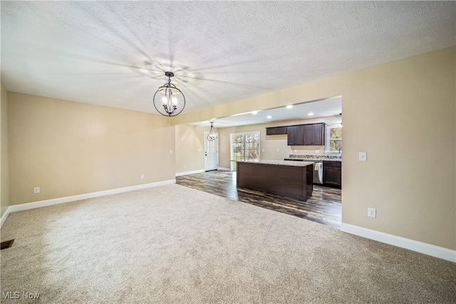 unfurnished living room featuring a textured ceiling, dark hardwood / wood-style floors, and an inviting chandelier