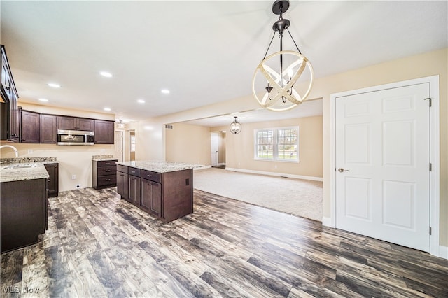 kitchen with dark brown cabinetry, sink, a notable chandelier, a center island, and pendant lighting