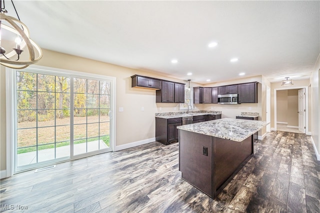 kitchen featuring hardwood / wood-style floors, appliances with stainless steel finishes, sink, and decorative light fixtures