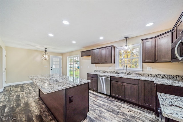 kitchen with appliances with stainless steel finishes, hardwood / wood-style floors, dark brown cabinets, and hanging light fixtures