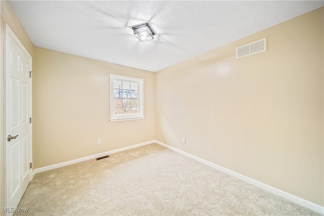 carpeted empty room with a textured ceiling