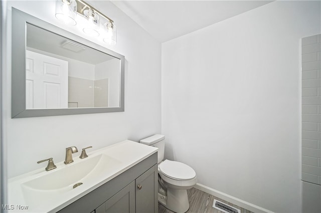 bathroom featuring walk in shower, hardwood / wood-style floors, vanity, and toilet