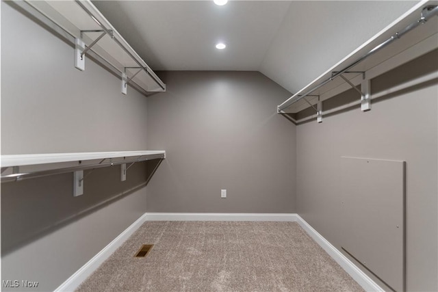 walk in closet with carpet and lofted ceiling