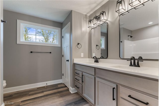 bathroom with hardwood / wood-style flooring, plenty of natural light, toilet, and vanity