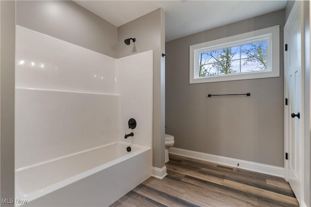 bathroom featuring bathing tub / shower combination, hardwood / wood-style flooring, and toilet