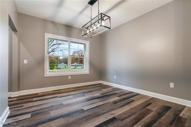 unfurnished dining area featuring dark wood-type flooring and a notable chandelier