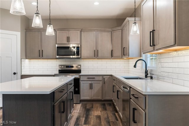 kitchen featuring pendant lighting, sink, tasteful backsplash, a kitchen island, and stainless steel appliances