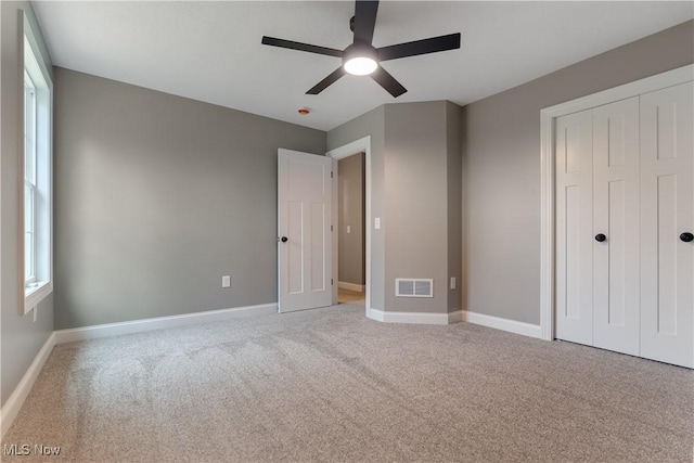 unfurnished bedroom featuring ceiling fan, light carpet, and a closet