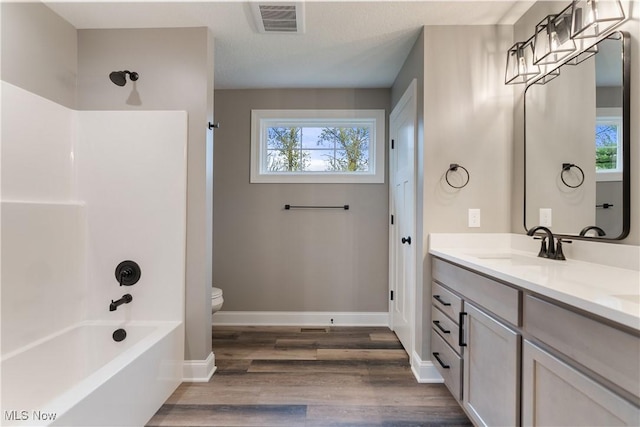 full bathroom featuring toilet, wood-type flooring, vanity, and bathing tub / shower combination