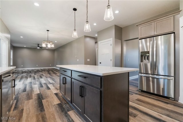 kitchen featuring ceiling fan, a kitchen island, hanging light fixtures, and appliances with stainless steel finishes