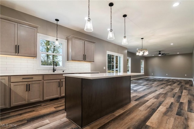 kitchen featuring ceiling fan, sink, backsplash, pendant lighting, and a kitchen island