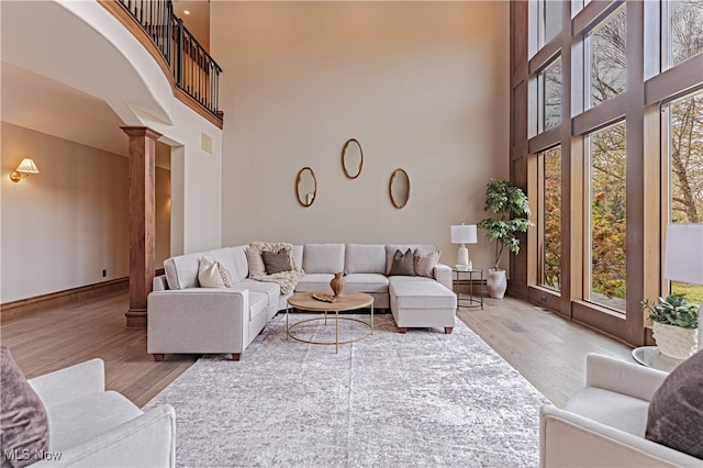 living room featuring a high ceiling, hardwood / wood-style flooring, ornate columns, and plenty of natural light