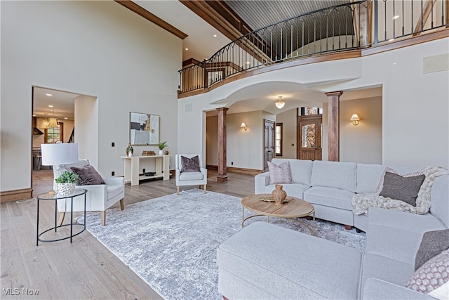 living room featuring a high ceiling, decorative columns, and hardwood / wood-style floors