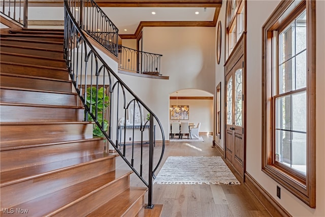 foyer with a towering ceiling, an inviting chandelier, and light wood-type flooring