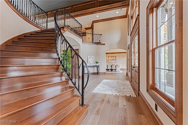 entrance foyer with a towering ceiling, a wealth of natural light, light hardwood / wood-style floors, and a chandelier