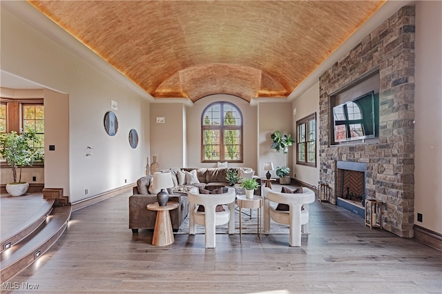 living room featuring a stone fireplace, brick ceiling, lofted ceiling, and hardwood / wood-style floors