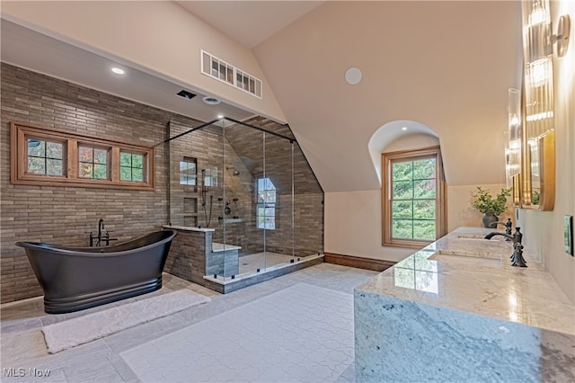 bathroom with independent shower and bath, vanity, vaulted ceiling, and brick wall