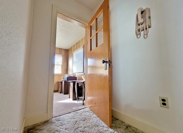 hallway with light carpet and wood walls