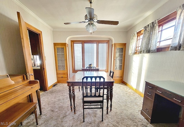 carpeted dining room featuring ceiling fan and crown molding