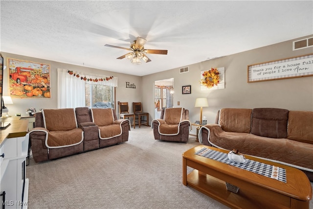 living room featuring a textured ceiling, light colored carpet, and ceiling fan