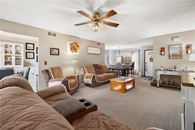 carpeted living room with ceiling fan with notable chandelier and a textured ceiling