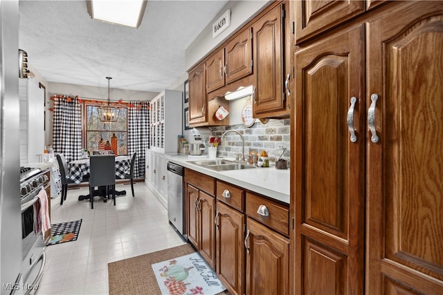 kitchen with stainless steel appliances, a textured ceiling, pendant lighting, an inviting chandelier, and sink