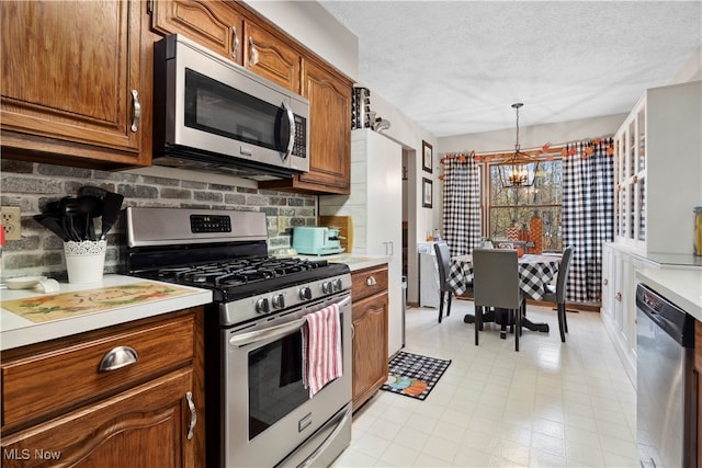 kitchen featuring a chandelier, pendant lighting, appliances with stainless steel finishes, and a textured ceiling