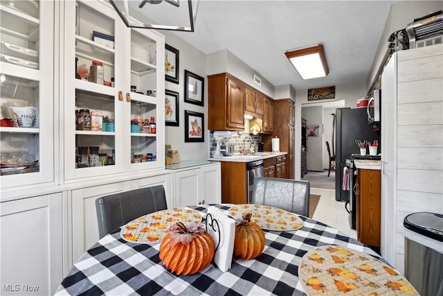 kitchen with backsplash, sink, light tile patterned floors, and stainless steel appliances