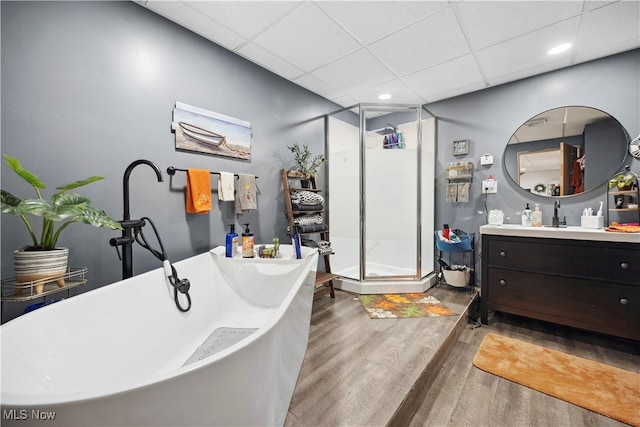 bathroom with wood-type flooring, vanity, separate shower and tub, and a paneled ceiling