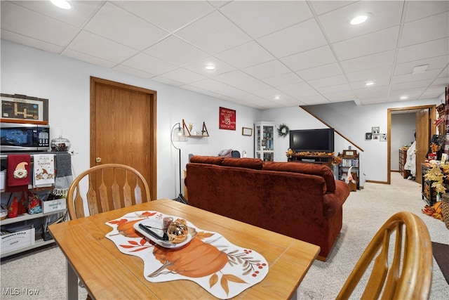 carpeted dining area with a paneled ceiling