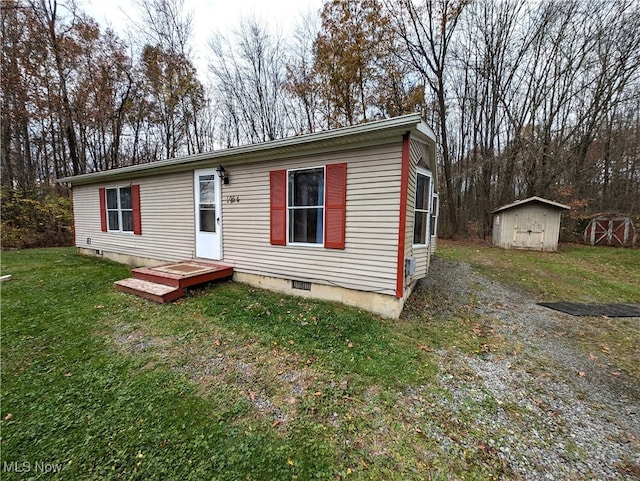 manufactured / mobile home featuring a front lawn and a storage shed