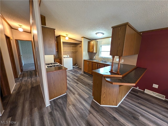 kitchen featuring a kitchen breakfast bar, a textured ceiling, dark hardwood / wood-style floors, and washer / dryer