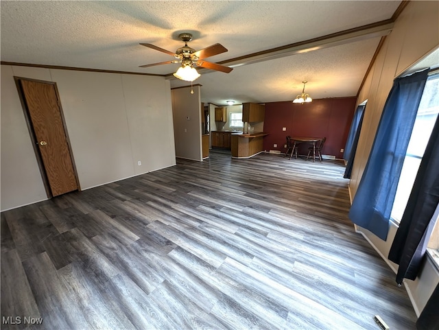 unfurnished living room with dark hardwood / wood-style floors, a healthy amount of sunlight, a textured ceiling, and crown molding