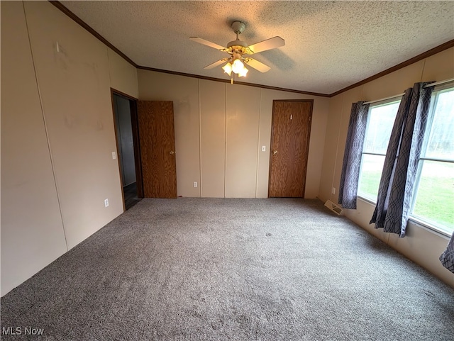 carpeted spare room featuring lofted ceiling, a textured ceiling, ceiling fan, and crown molding