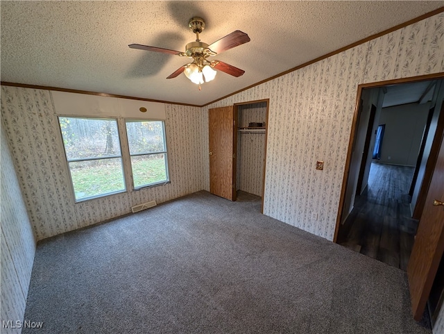 unfurnished bedroom featuring ornamental molding, vaulted ceiling, ceiling fan, and a textured ceiling