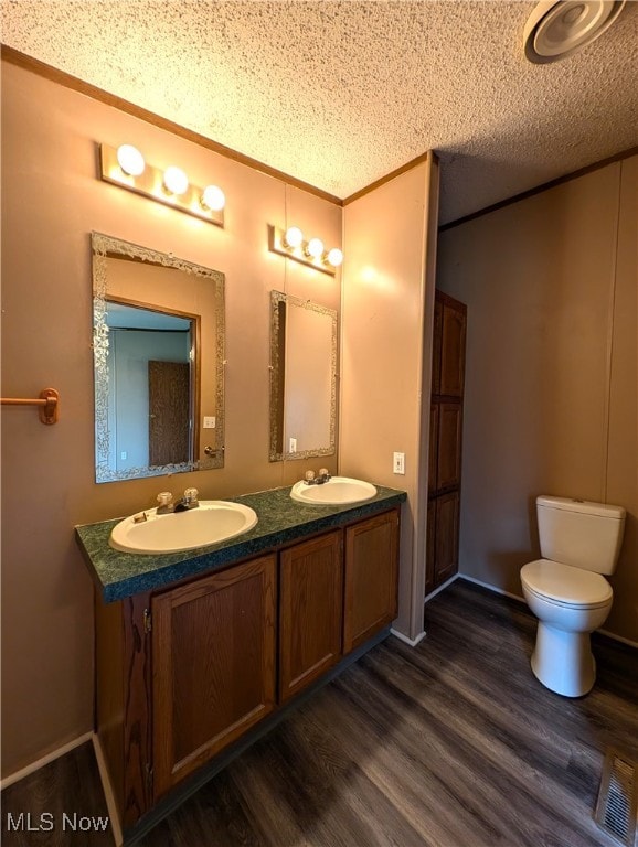 bathroom with ornamental molding, vanity, a textured ceiling, hardwood / wood-style flooring, and toilet