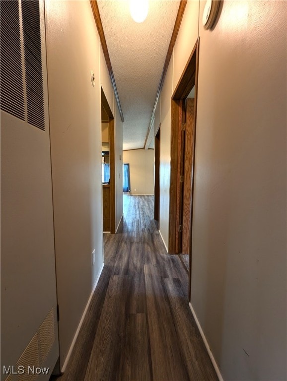 hall featuring dark hardwood / wood-style flooring, a textured ceiling, and ornamental molding