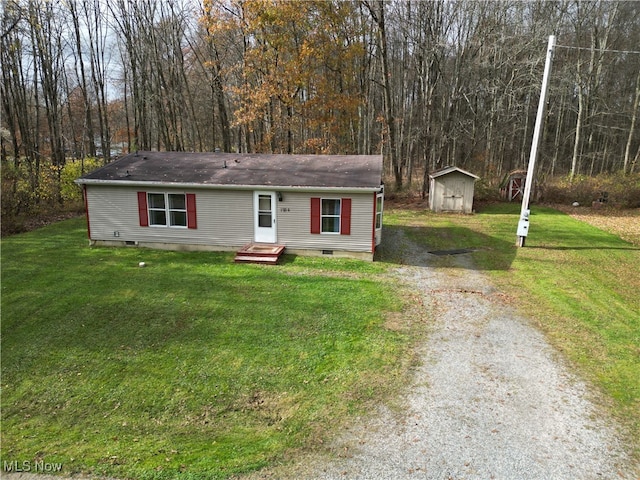 view of front of property featuring a front lawn and a shed